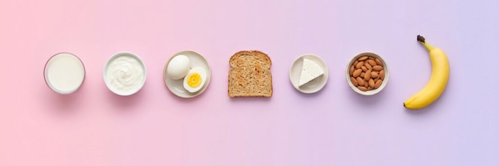 Fila de alimentos de desayuno rico en proteína sobre fondo degradado rosa y lila